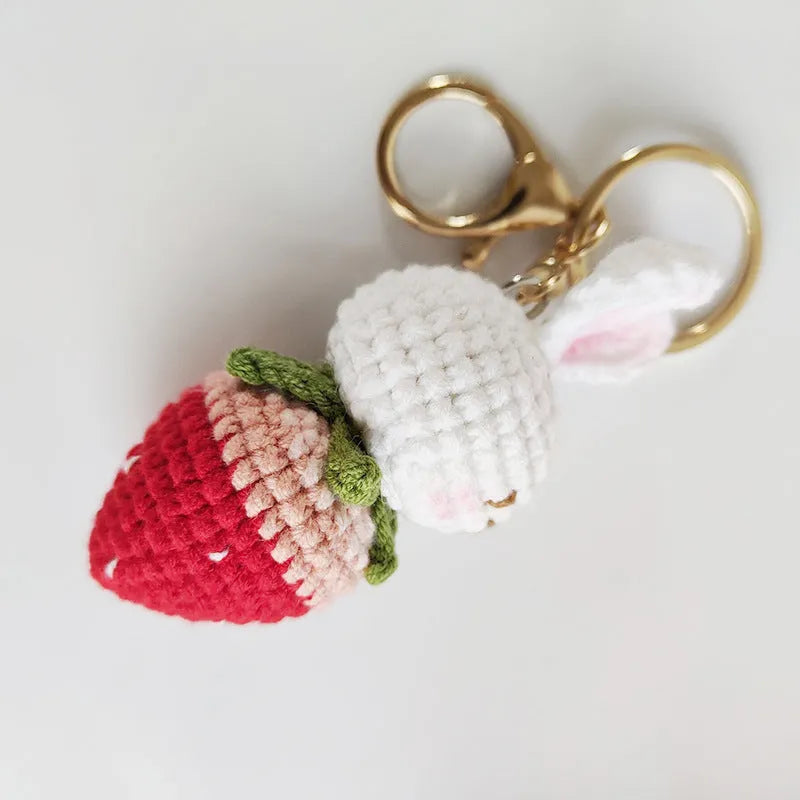 Hand-woven white doll wire rabbit strawberry pendant on a key chain.