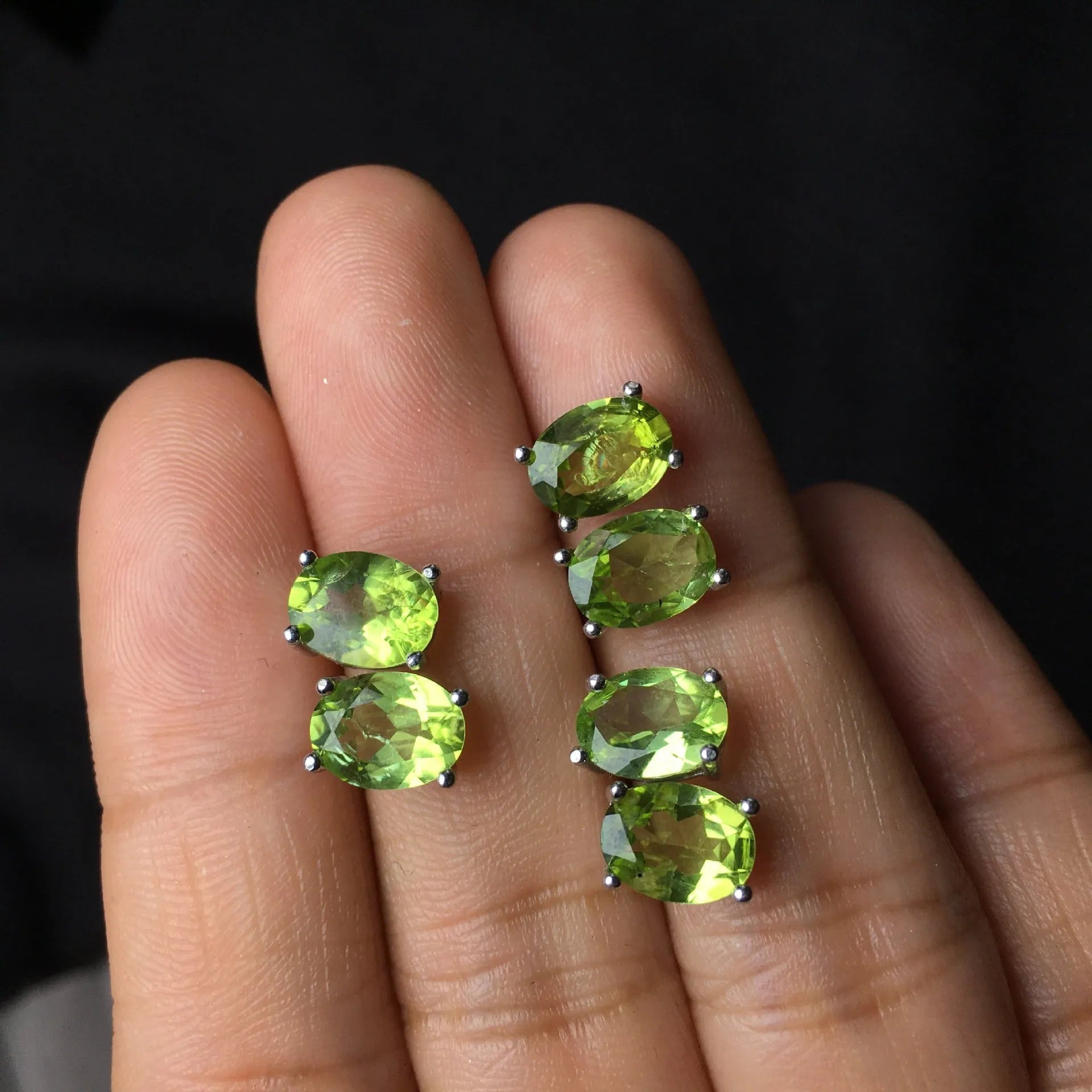 Close-up of grass green natural olivine faceted stud earrings in S925 silver geometric setting.