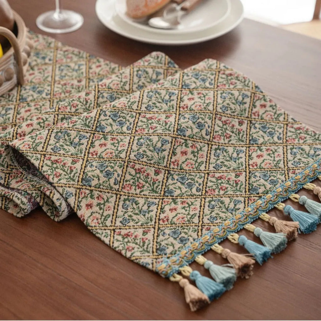 Dark blue striped jacquard table runner with tassel trim laid on a wooden table.