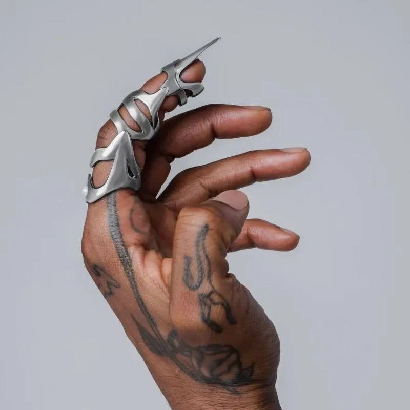 Silver-coloured alloy finger stall with a punk armour design.