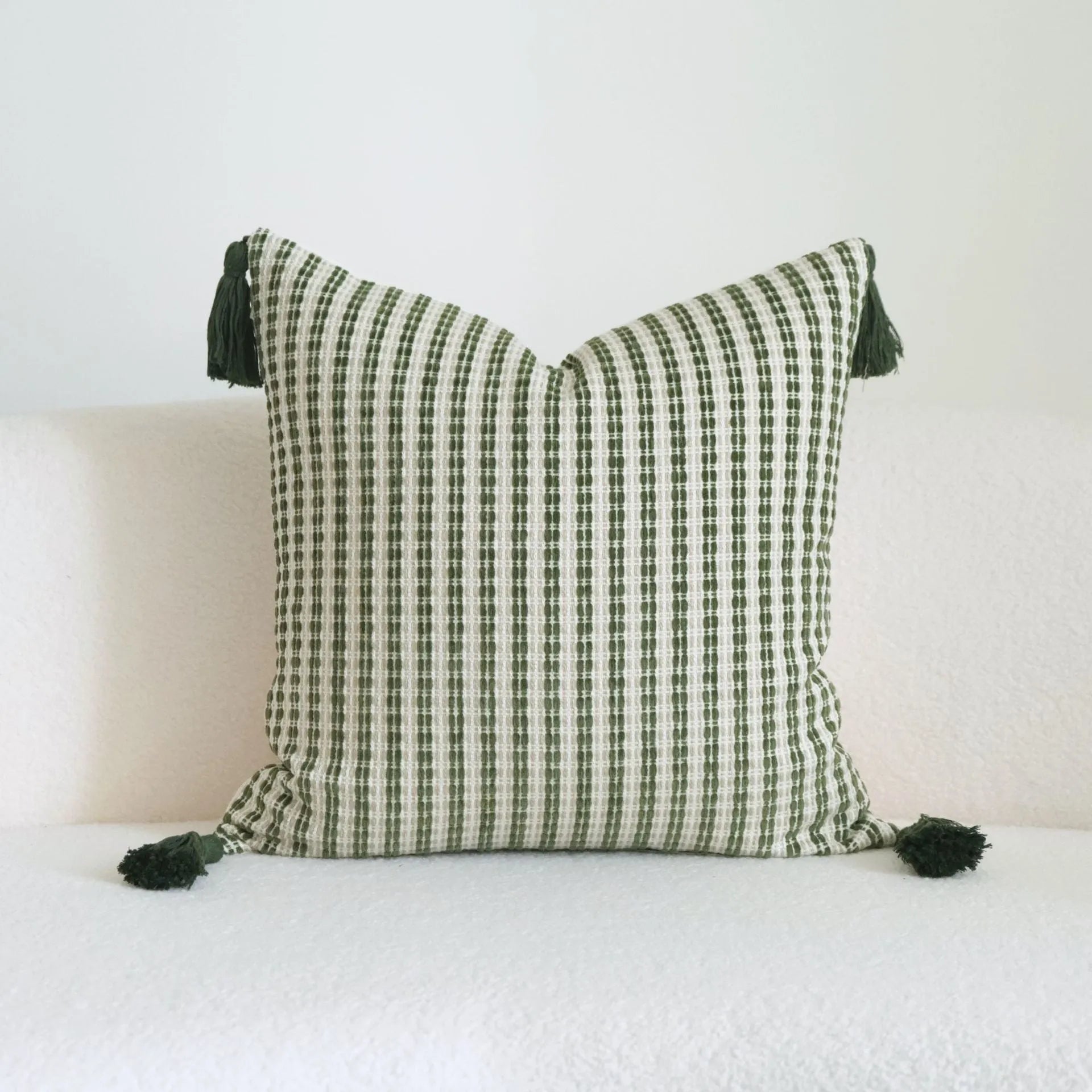 Green decorative pillow with tassel or beaded design on a cotton linen blend cover.