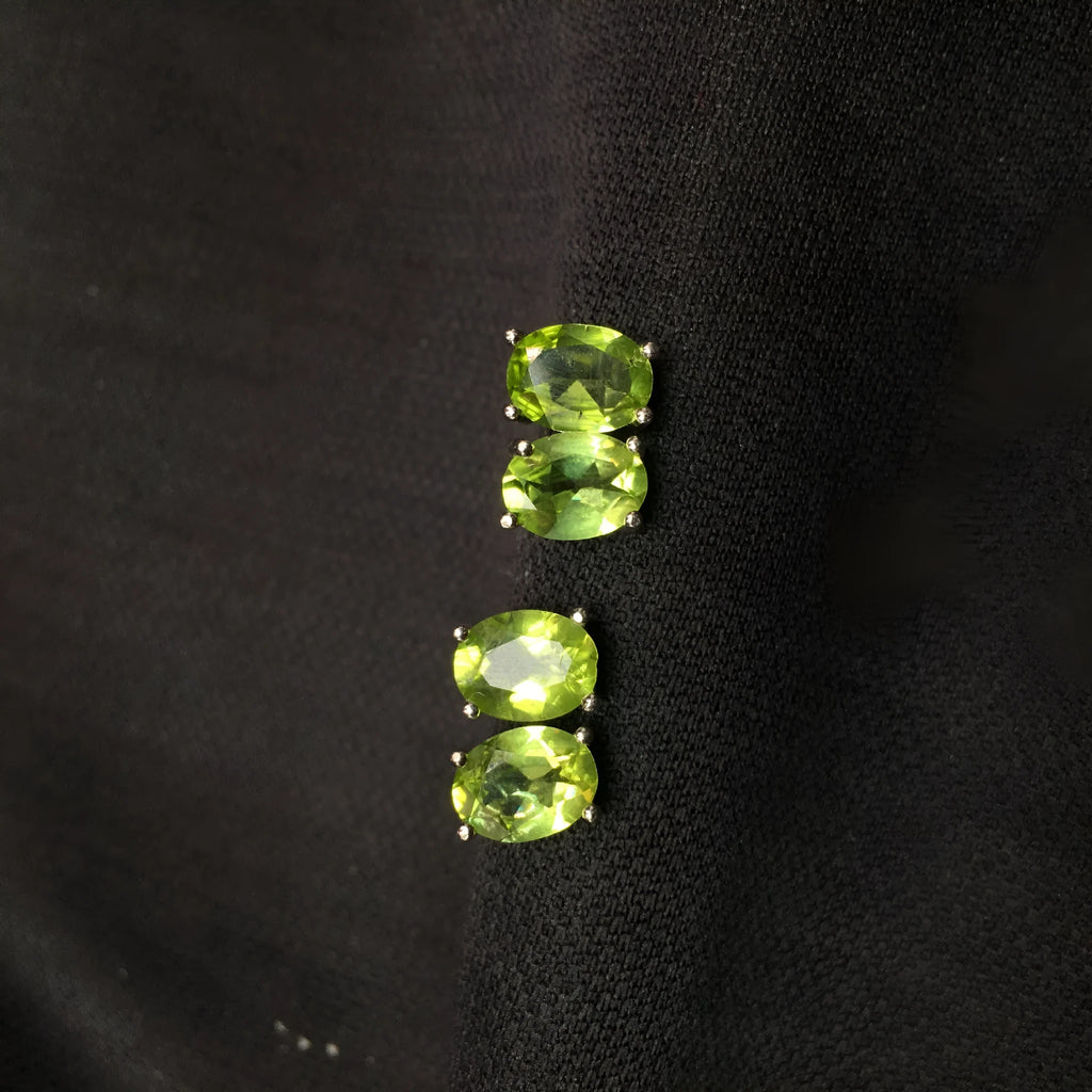 Close-up of grass green natural olivine faceted stud earrings in S925 silver geometric setting.