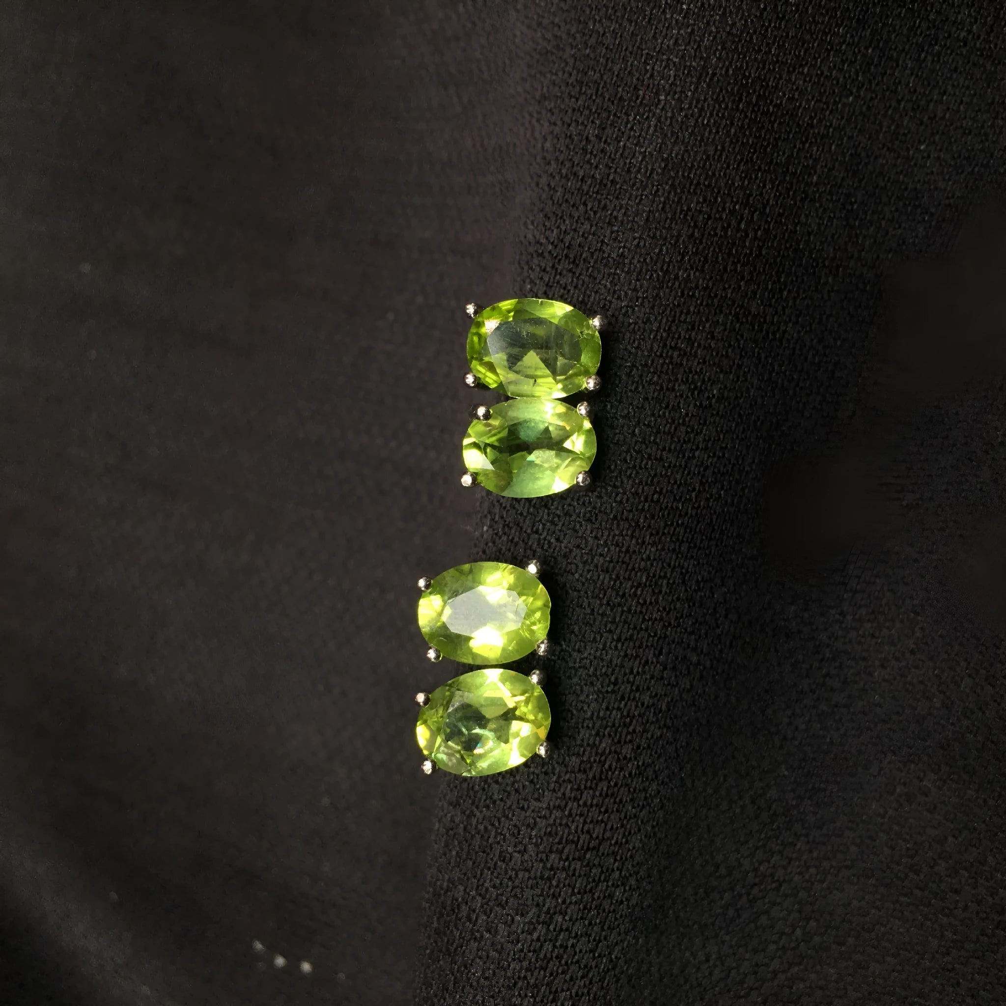 Close-up of grass green natural olivine faceted stud earrings in S925 silver geometric setting.