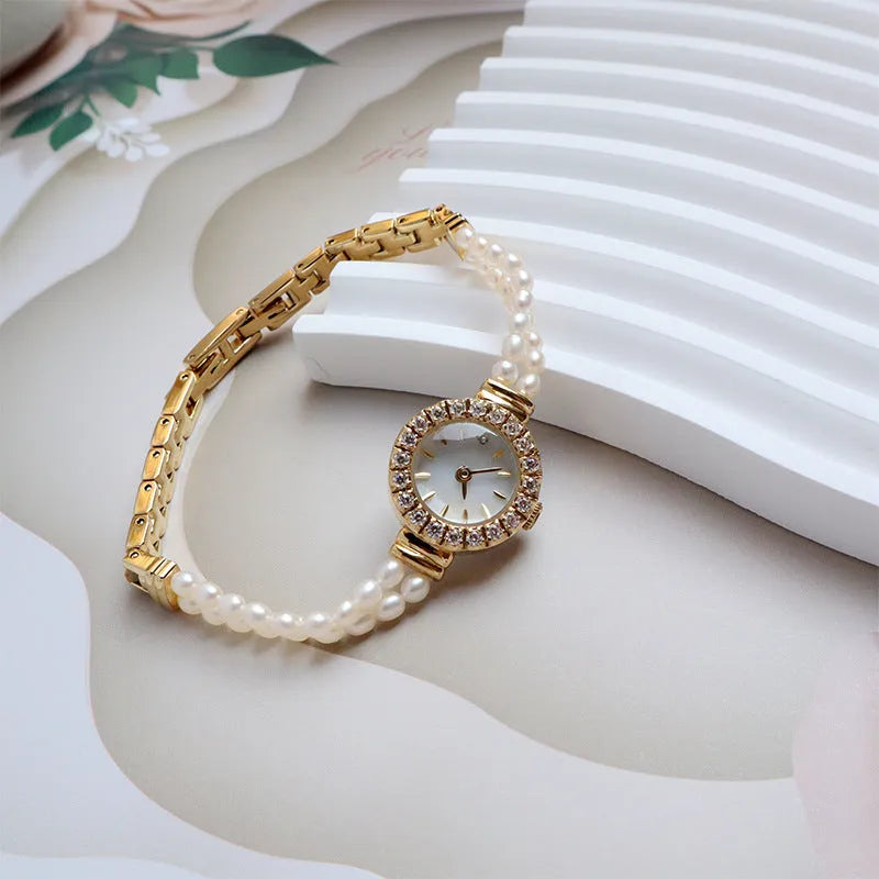 Light gold women's bracelet watch with freshwater pearls, round 18mm dial, and stainless steel strap.