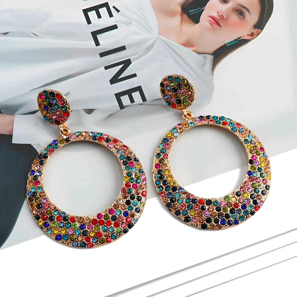 A pair of large round pendant earrings with colourful diamond-like accents on a metal alloy base, cartoon style.