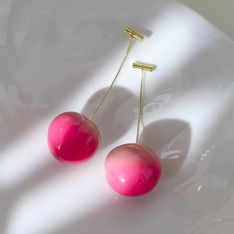 A pair of peach-shaped acrylic earrings on copper posts, shown in small and large size options.