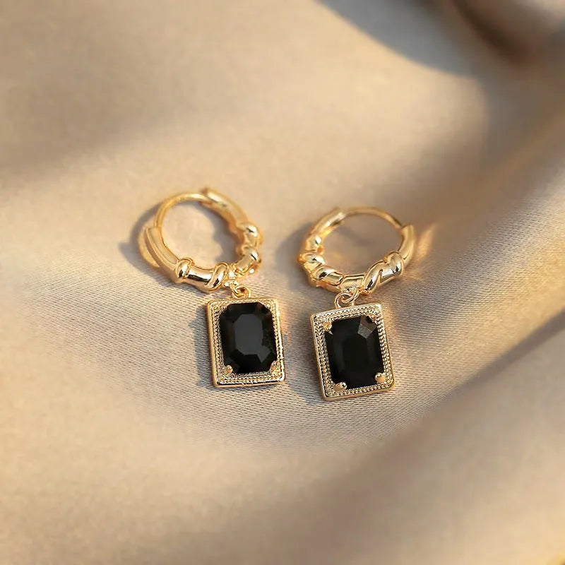 Close-up of black geometric quadrilateral stud earrings with zircon stones on a French court wire.