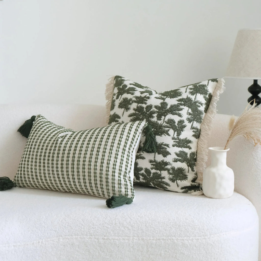 Green decorative pillow with tassel or beaded design on a cotton linen blend cover.