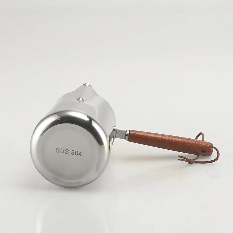 Stainless steel coffee milk jug with wooden handle and measuring scale for latte art.