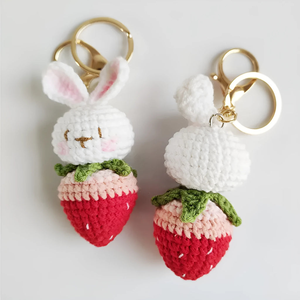 Hand-woven white doll wire rabbit strawberry pendant on a key chain.