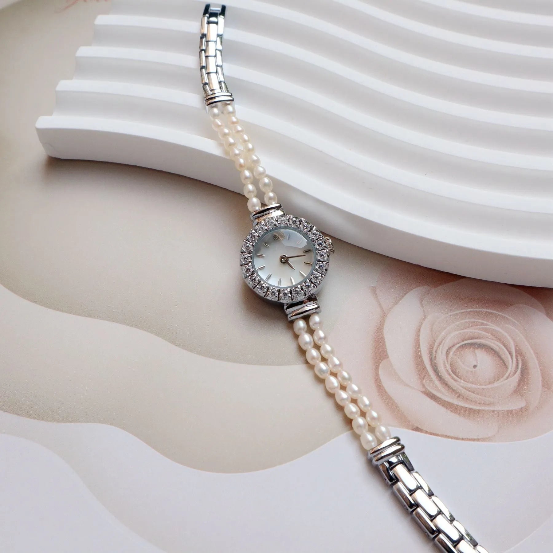 Light gold women's bracelet watch with freshwater pearls, round 18mm dial, and stainless steel strap.