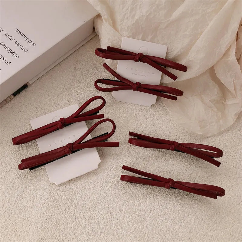 Wine red leather bow hair barrette on a white background.