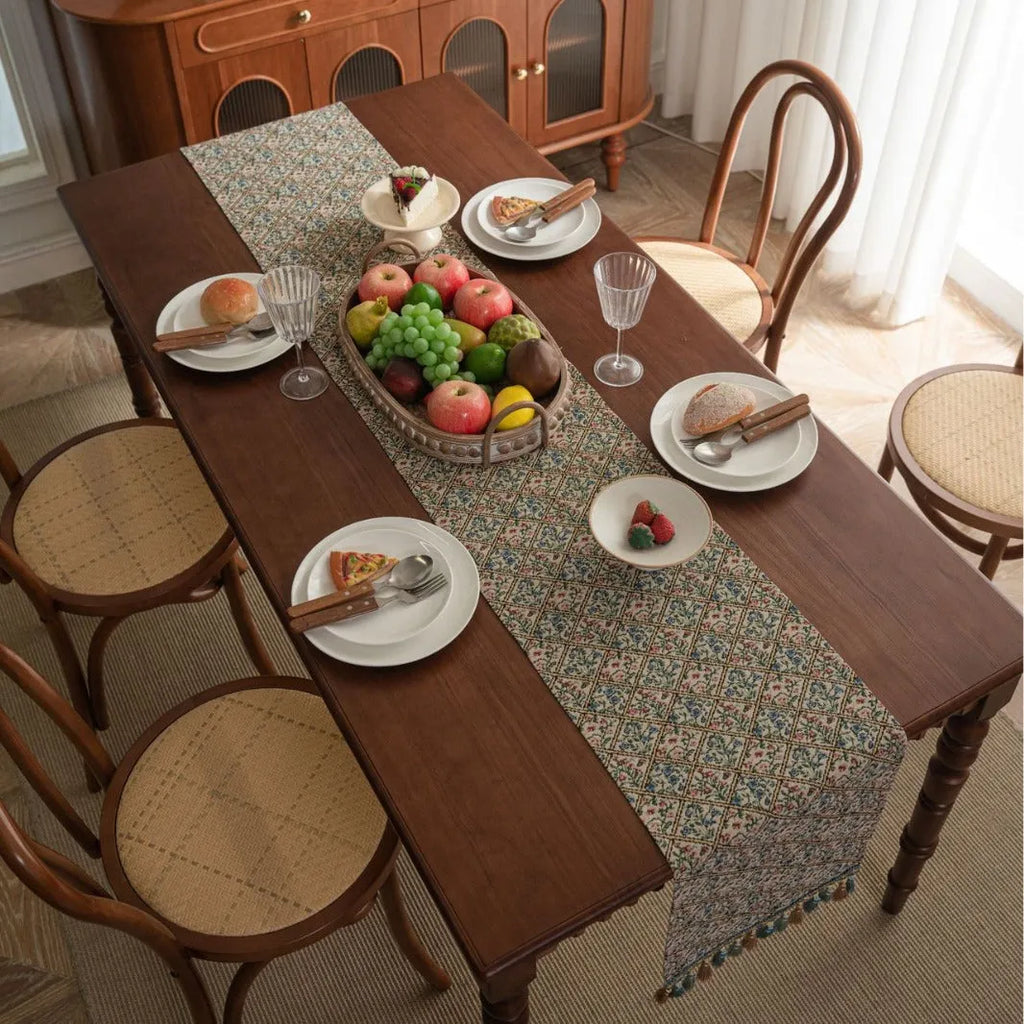 Dark blue striped jacquard table runner with tassel trim laid on a wooden table.