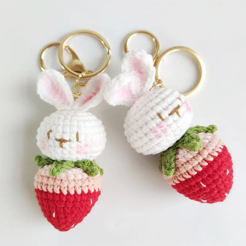 Hand-woven white doll wire rabbit strawberry pendant on a key chain.