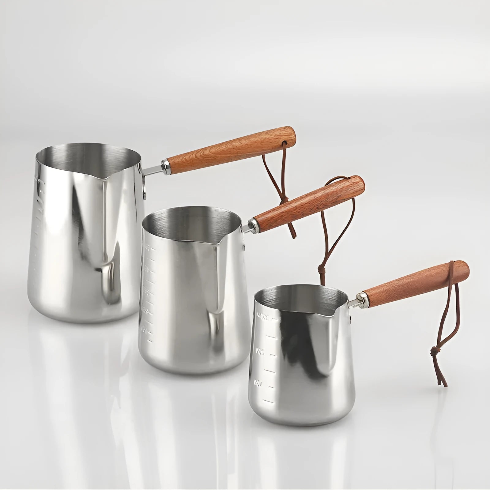Stainless steel coffee milk jug with wooden handle and measuring scale for latte art.