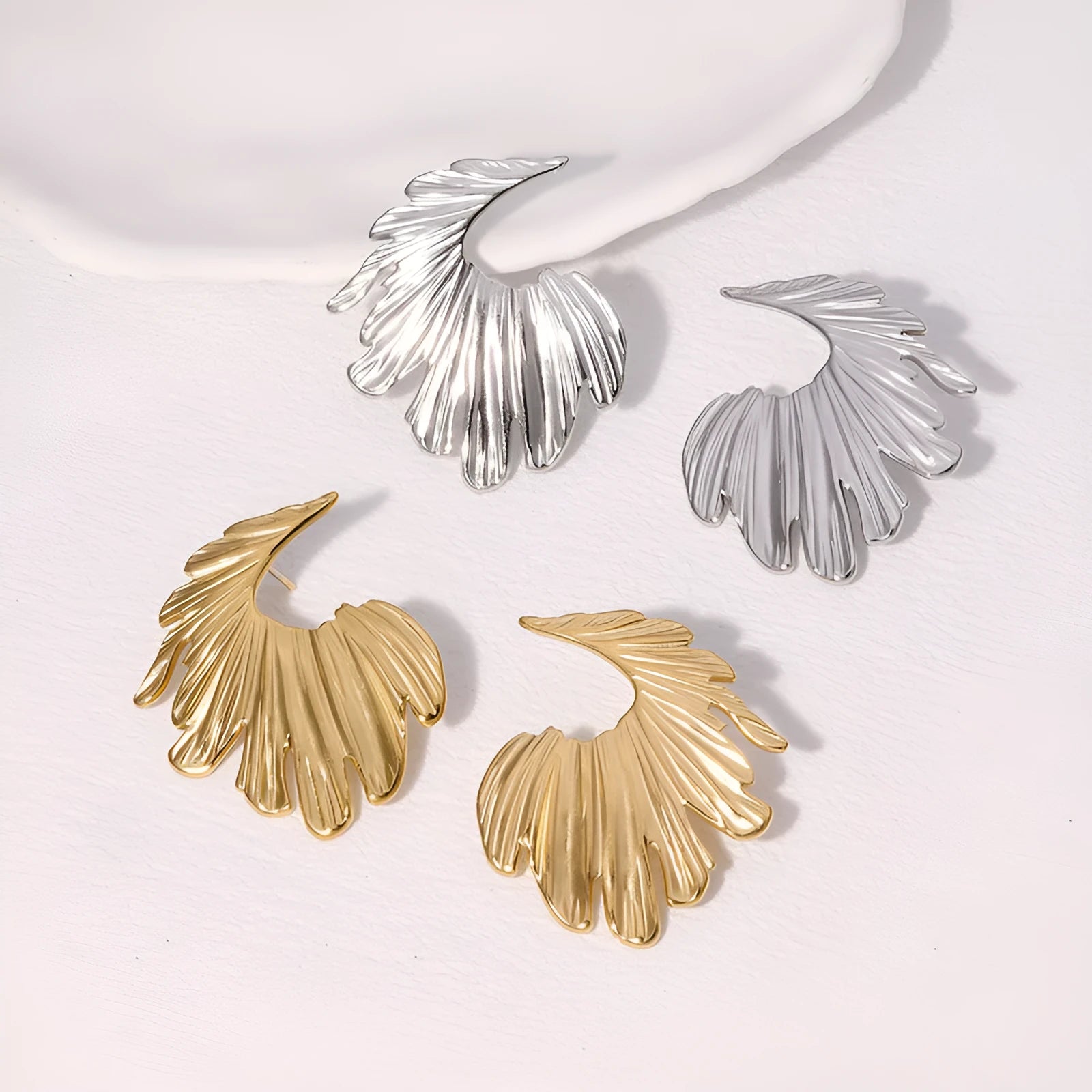 A pair of stainless steel earrings in a leaves shape with a gold electroplated finish.