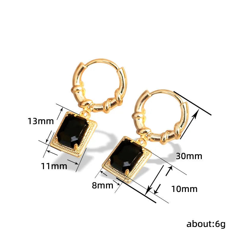 Close-up of black geometric quadrilateral stud earrings with zircon stones on a French court wire.