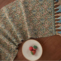 Dark blue striped jacquard table runner with tassel trim laid on a wooden table.
