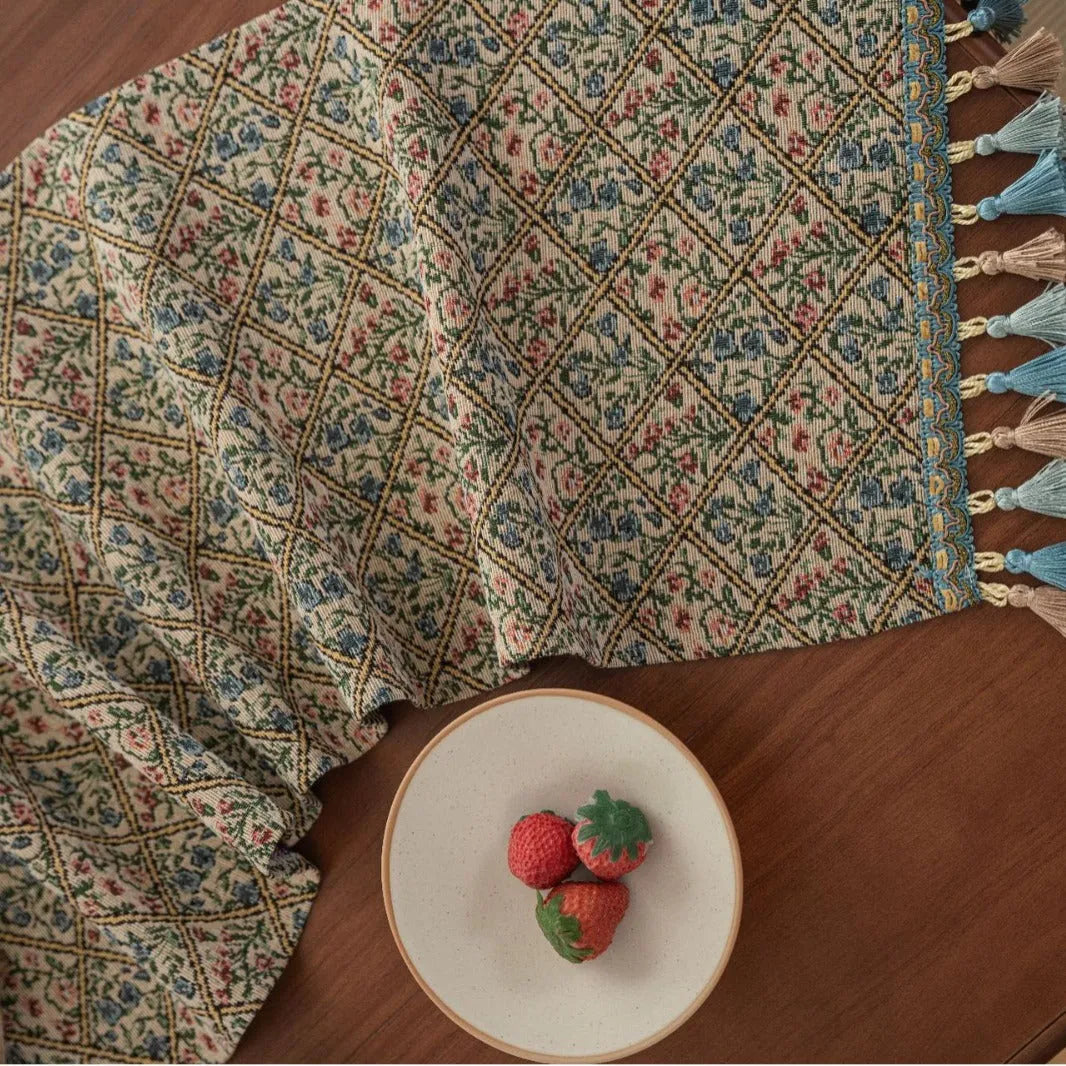 Dark blue striped jacquard table runner with tassel trim laid on a wooden table.
