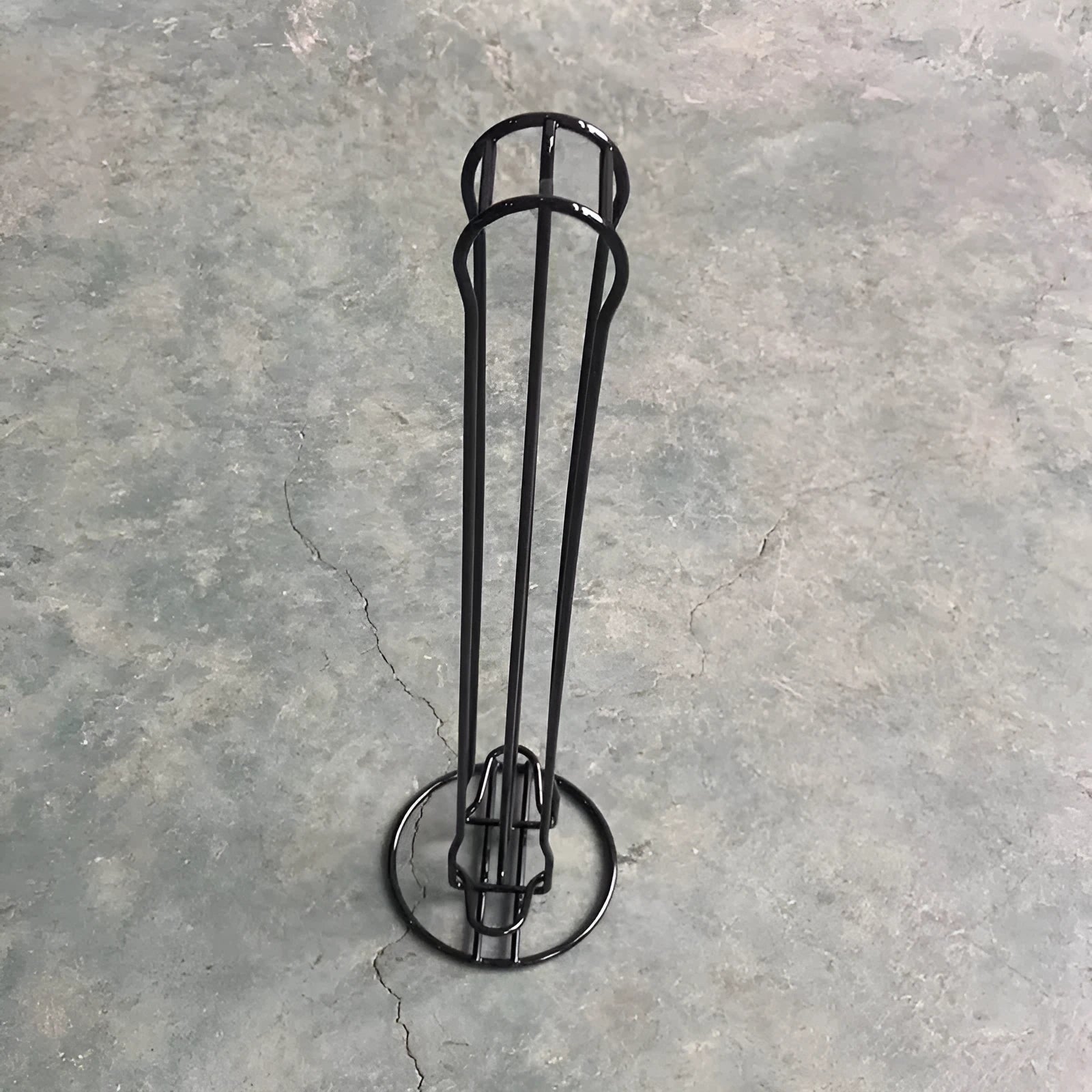 Black wrought iron coffee capsule storage rack holding pods on shelving, modern simple design.