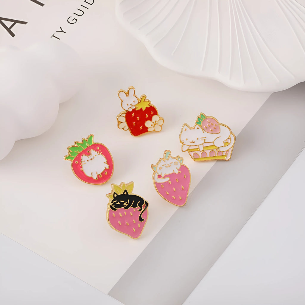 Close-up of a cute cat strawberry dripping oil cake design alloy metal brooch on a fabric background.