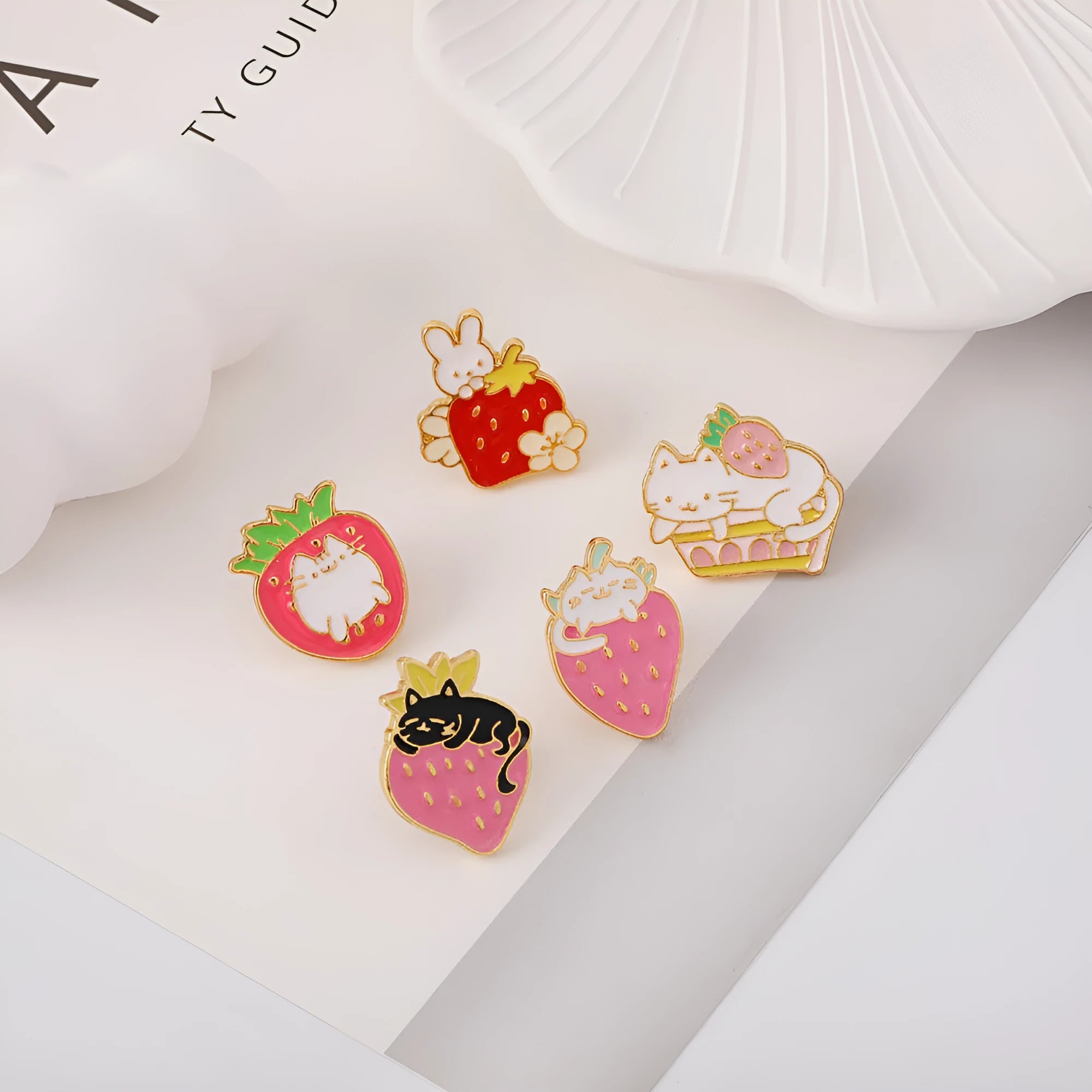 Close-up of a cute cat strawberry dripping oil cake design alloy metal brooch on a fabric background.