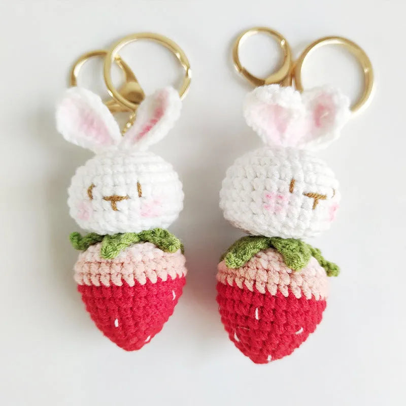 Hand-woven white doll wire rabbit strawberry pendant on a key chain.