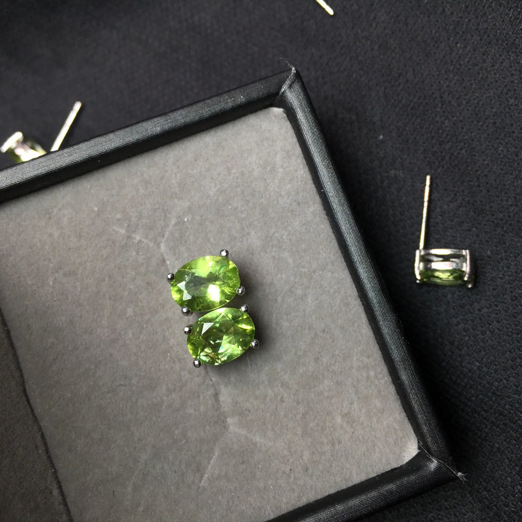 Close-up of grass green natural olivine faceted stud earrings in S925 silver geometric setting.