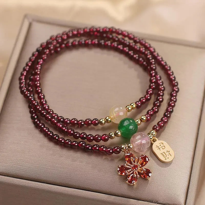 Women's natural crystal bracelet in pomegranate red cherry blossom colour with sequin details on strap.