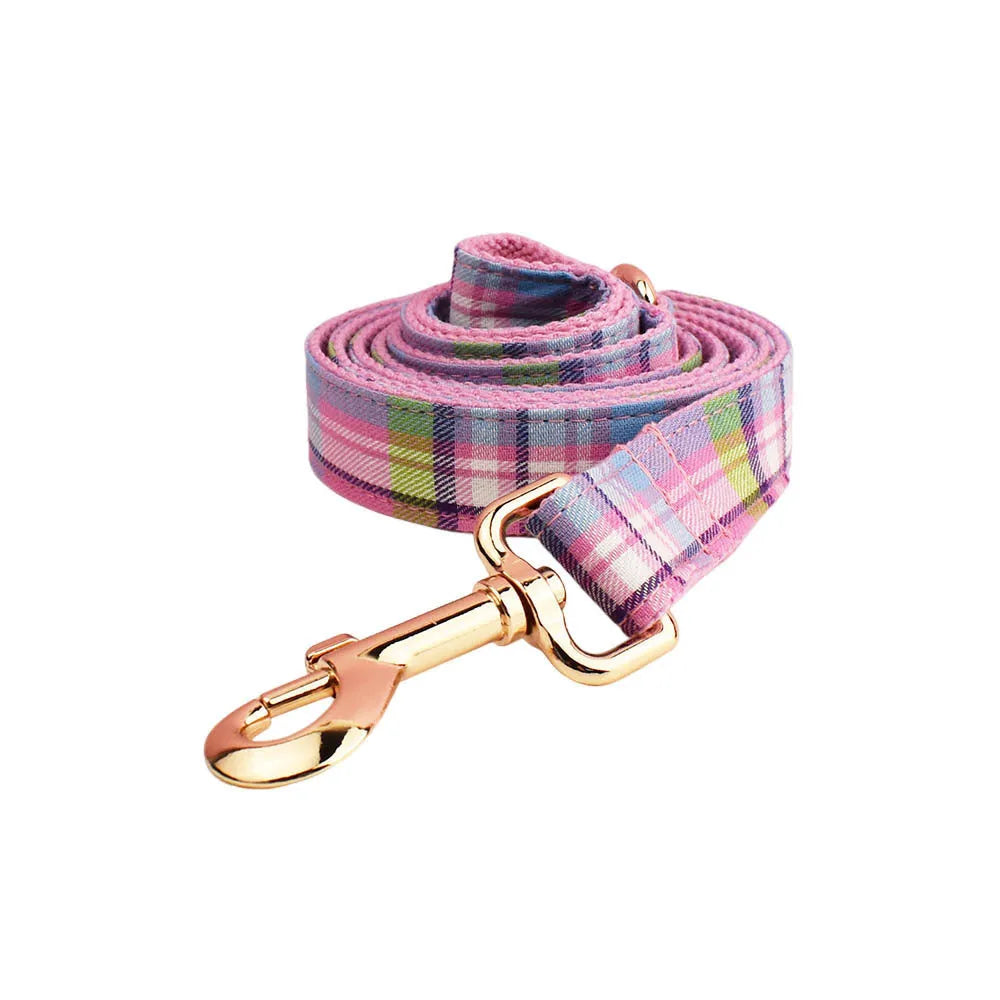 Cloth dog collar and matching lead set with a red bow and a matching dog vest laid out flat.