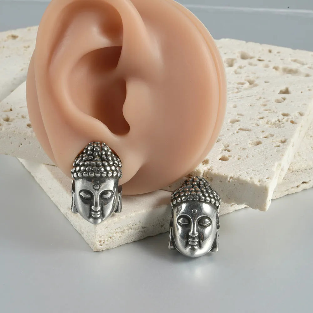 Stainless steel hollow geometric earrings combining a skull with a Buddha head motif.