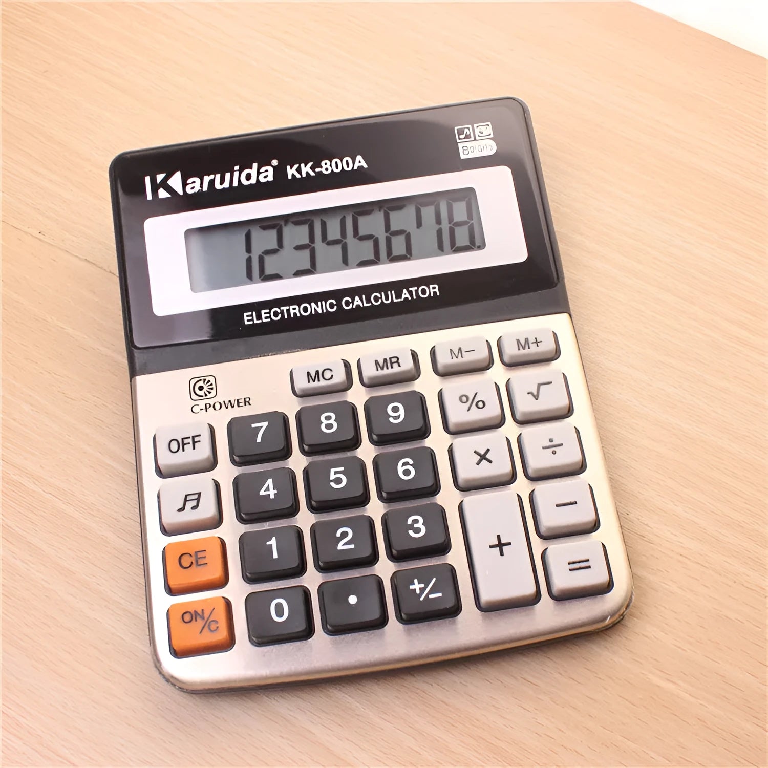 Compact silver aluminium desktop pocket calculator on a desk surface, approximate dimensions 14.5 x 11 x 2.5 cm