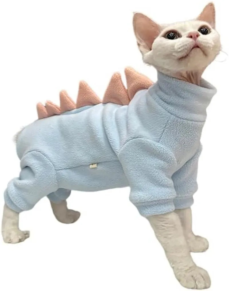 Sphynx cat wearing a green fleece dinosaur costume with a tail and back spikes