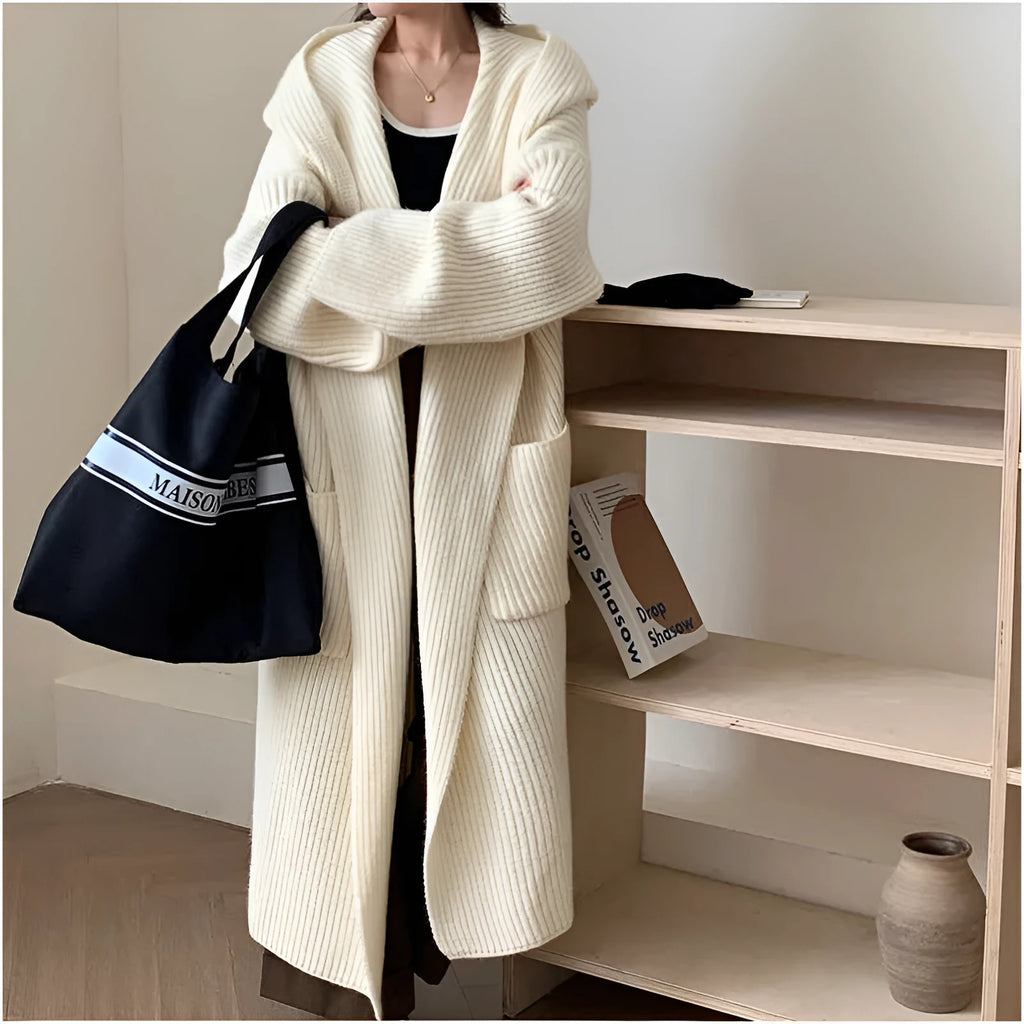 Woman wearing a loose beige hooded zip-front cardigan coat with raglan sleeves.