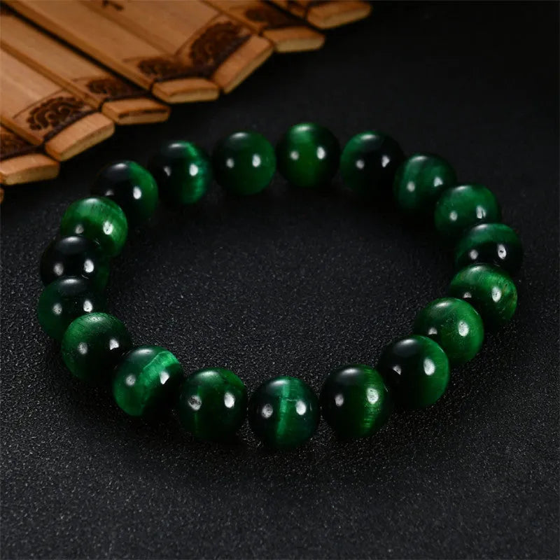 Natural green tiger eye stone bracelet with polished spherical beads in geometric design on wrist.