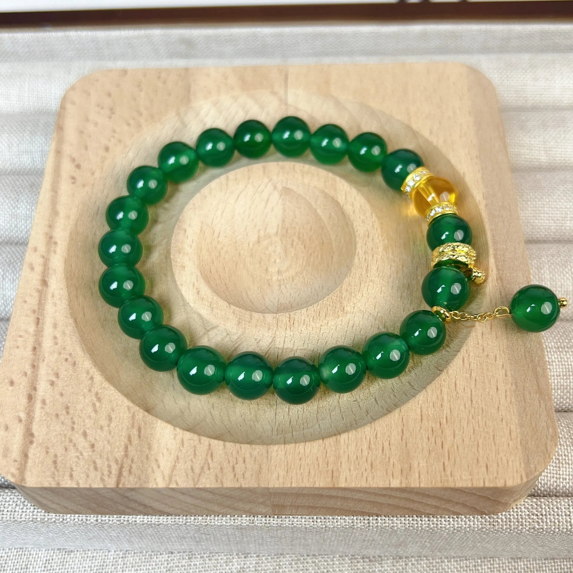 Green and red agate stone bead wealth snake bracelet with copper details on a wrist.