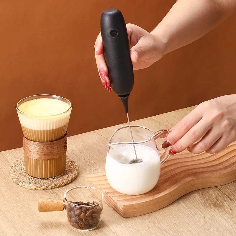 Electric hand-held milk frother blender in black and white colour options on a kitchen counter.
