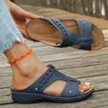 Women's blue Roman style slope heel slippers with fish mouth toe holder on a wooden floor.