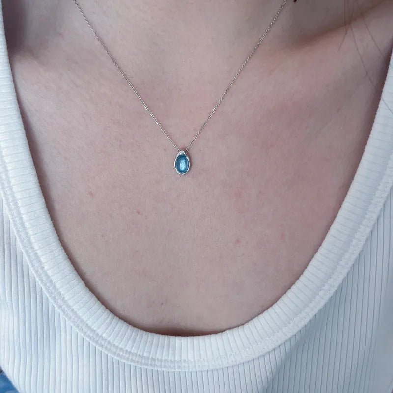 Geometric navy blue water drop pendant on an adjustable copper cross necklace for women.