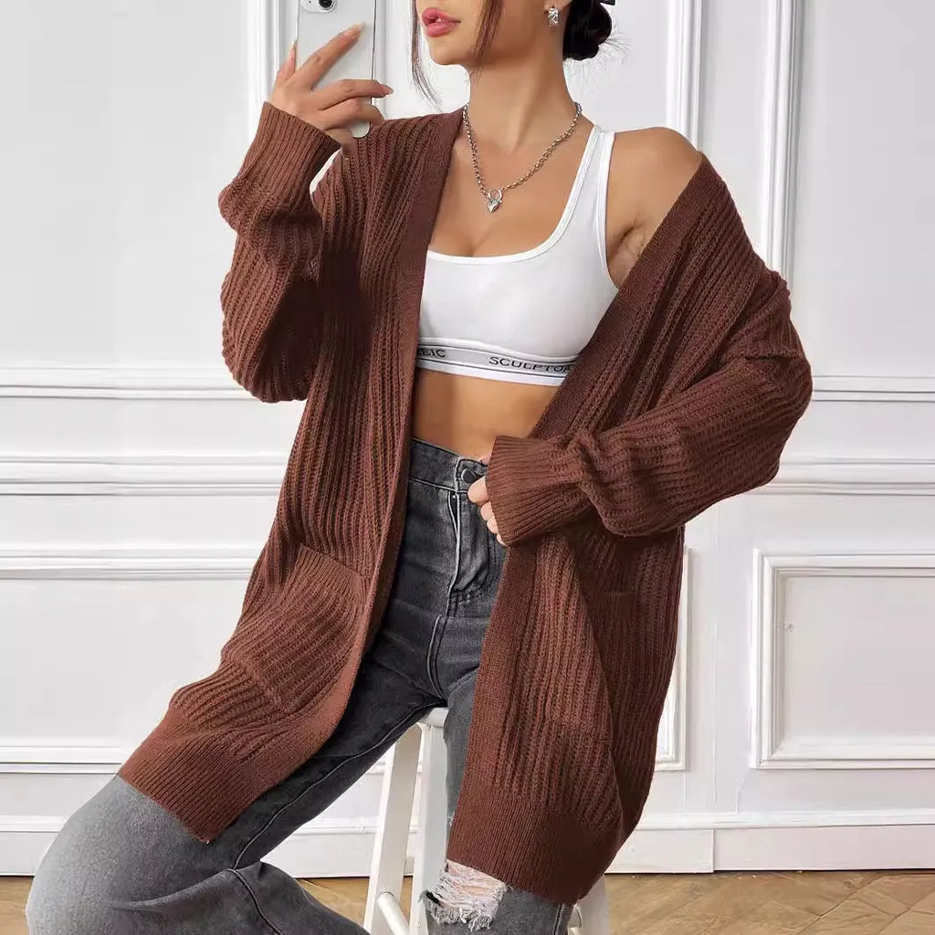 A woman's loose-fit acrylic cardigan in dark green with long sleeves and two front pockets.
