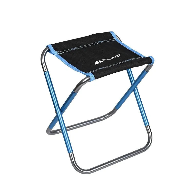 Black ethnic style aluminium alloy folding stool set up on grass.