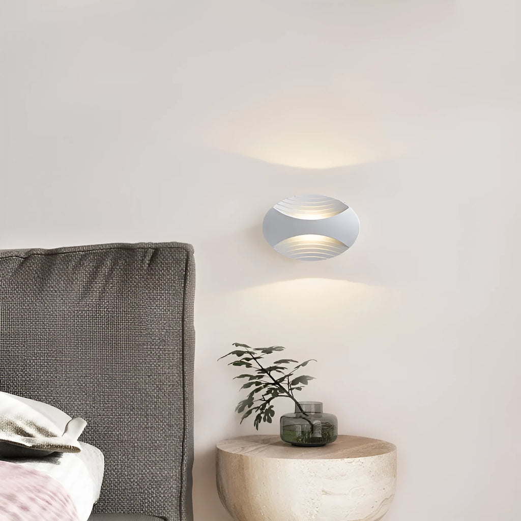 A modern aluminium wall lamp mounted beside a bed, showcasing its minimalist design.