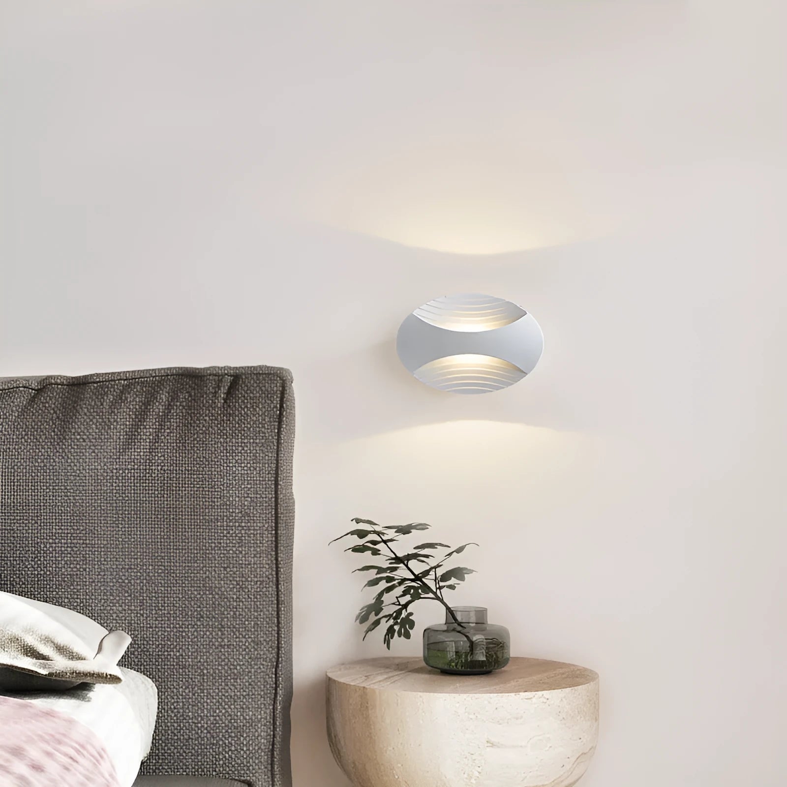 A modern aluminium wall lamp mounted beside a bed, showcasing its minimalist design.