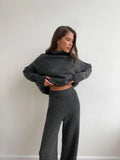 Women's dark grey acrylic knit sweater suit with side-slit top and matching trousers.