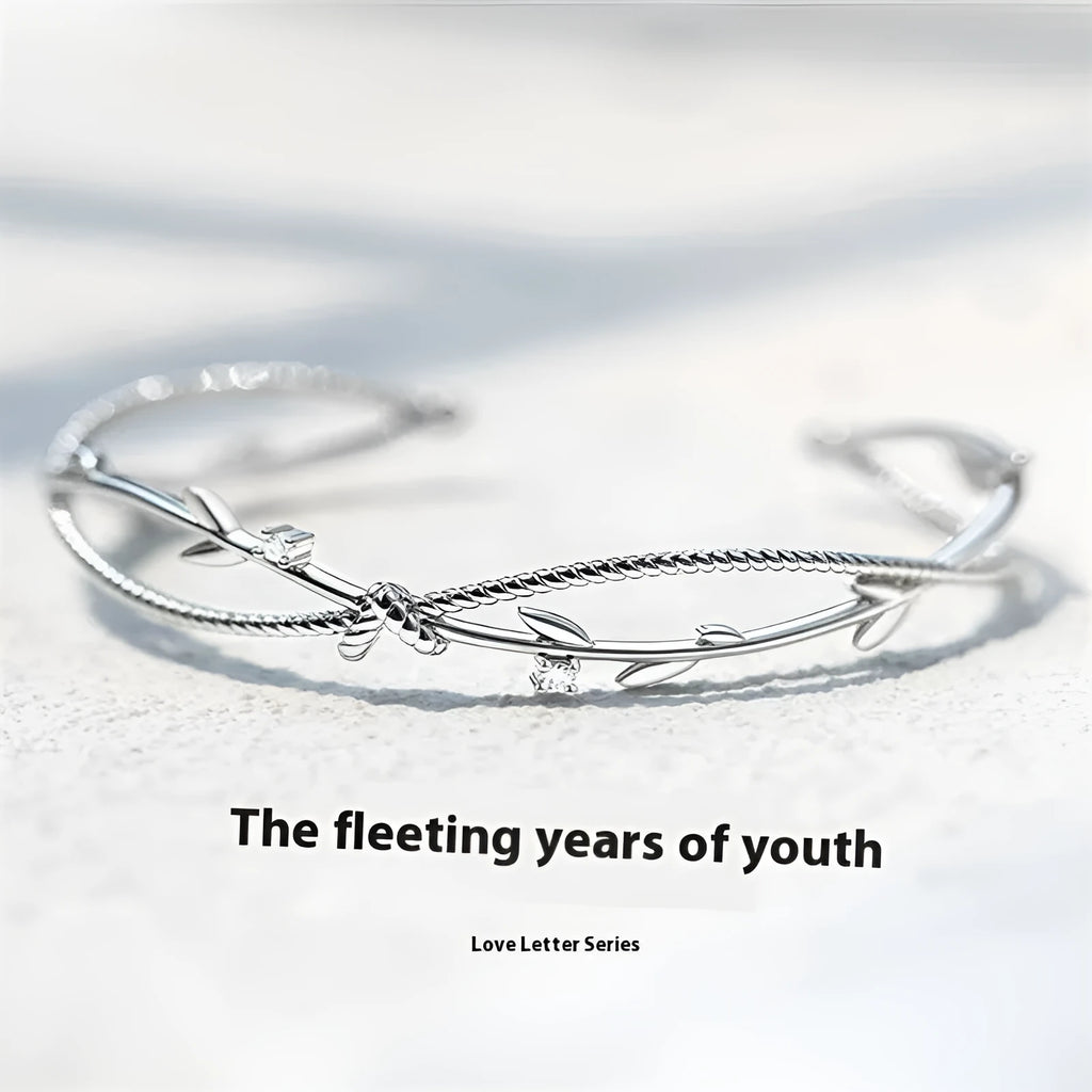 Close-up of a white gold coloured twisted branch sprout design bracelet on a wrist.