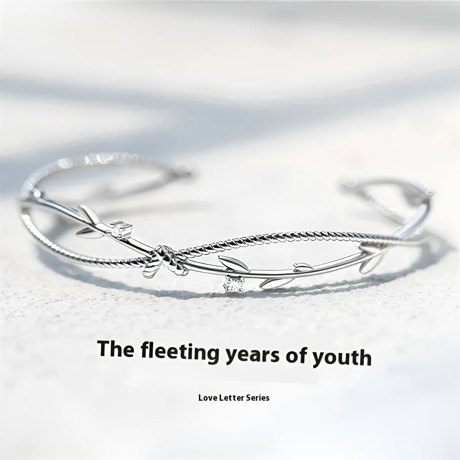 Close-up of a white gold coloured twisted branch sprout design bracelet on a wrist.
