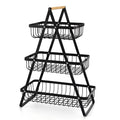 Black detachable iron double-layer fruit basket with a wooden handle on a kitchen counter.