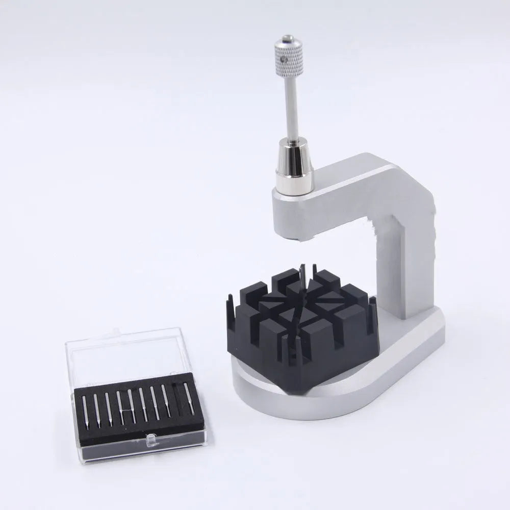 Silver tool steel press strap removal tool for watch and jewellery repair on a workbench.