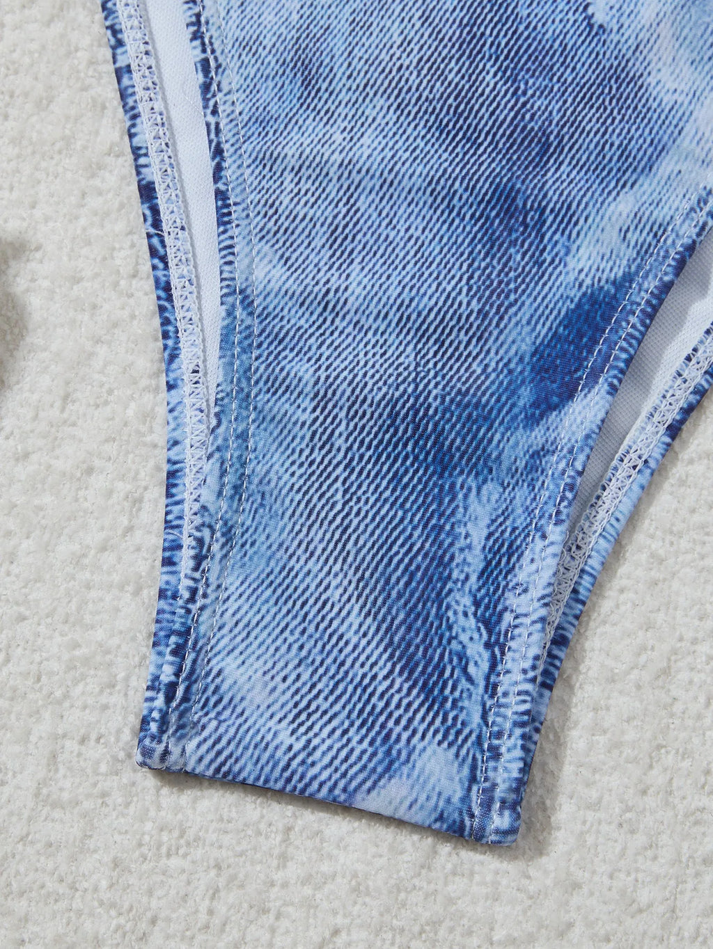Denim blue printed women's bikini swimsuit with adjustable straps laid flat.