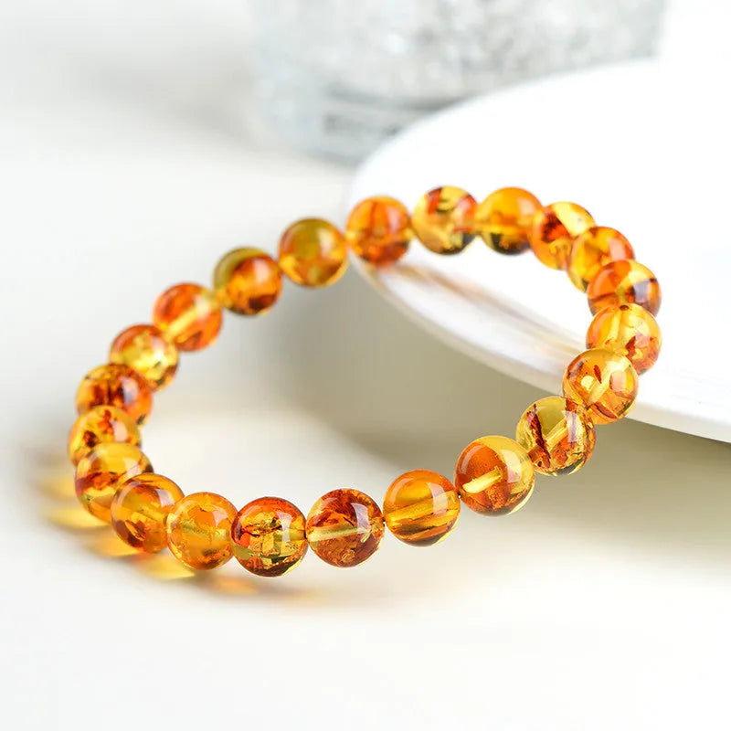 Natural yellow piebald amber geometric bracelet on a wrist, showing polished beads with flower spot patterning.